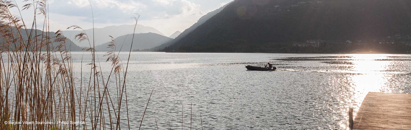 Blick von einem Steg über den Ossiacher See mit Boot